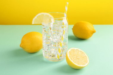 Refreshing water with ice and lemon on color background