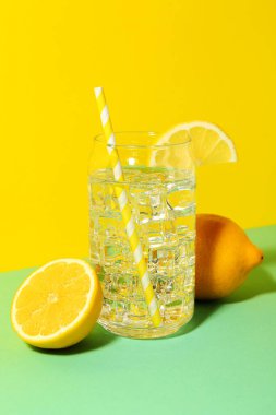 Refreshing water with ice and lemon on color background
