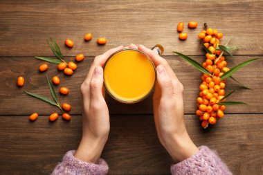 Ahşap masada deniz dikenli çay içen bir kadın.