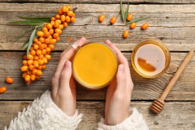 Ahşap masada deniz dikenli çay içen bir kadın.