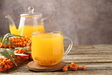 Sea buckthorn tea and fresh berries on wooden table, closeup. Space for text