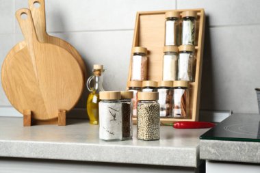 Different spices in glass jars on light grey table in kitchen