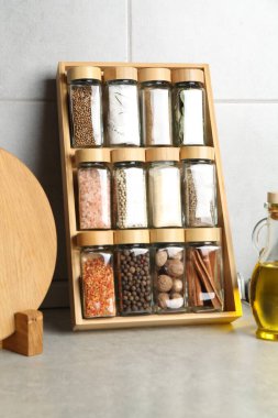 Cam kavanozlarda farklı baharatlar ve mutfakta açık gri masada yağlar.