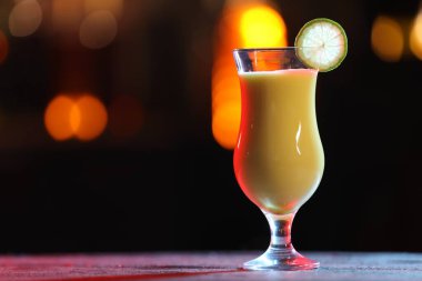 Arka planda bulanık arka planda garnitürlü bir bardak alkollü kokteyl, mesaj için yer var. Bokeh etkisi