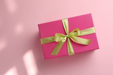 Pembe arka planda fiyonklu güzel bir hediye kutusu, üst manzara. Metin için boşluk