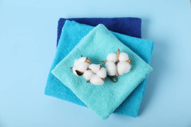 Temiz havlular ve açık mavi arka planda pamuk çiçekleri.