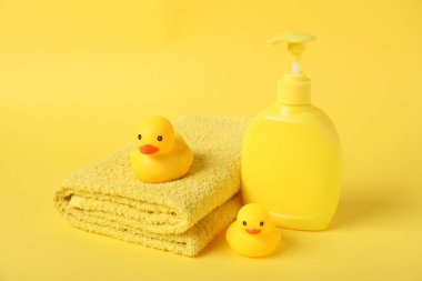 Taze havlu, kozmetik ürünler ve sarı arka planda plastik ördekler.