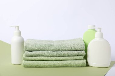 Renkli arka planda bir yığın temiz havlu ve kozmetik ürünler