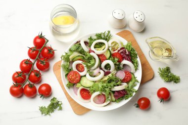 Delicious salad with squid rings and vegetables served on white marble table, flat lay