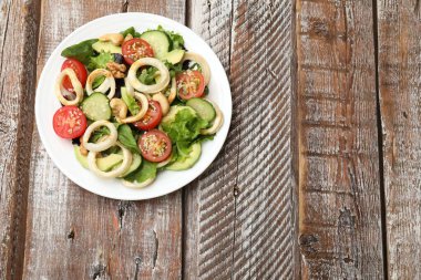 Kalamar halkalı lezzetli salata, avokado, ahşap masada fındık ve sebzeler, üst manzara. Metin için boşluk