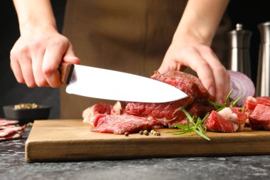 Karanlık masada çiğ et kesen kadın, yakın plan.