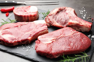 Çiğ et, baharat ve çatal parçaları gri masada, yakın plan.