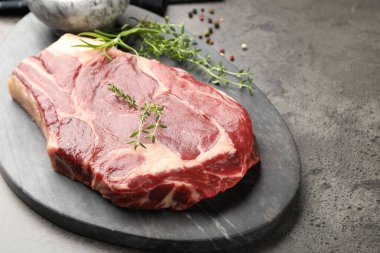 Piece of raw beef meat and spices on grey table, closeup. Space for text