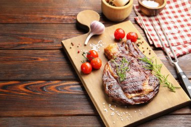 Ahşap masada otlu, baharatlı ve ürünlü leziz ızgara biftek, yakın plan. Metin için boşluk