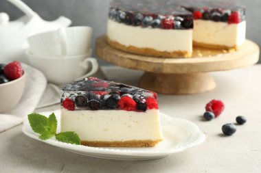 Piece of delicious cheesecake with berries and mint on light grey table, closeup
