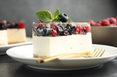 Lezzetli peynirli kek, böğürtlenli ve nane şekerli, siyah ahşap masa, yakın plan.