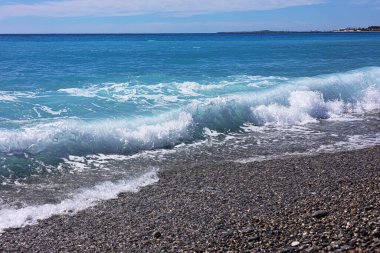 Beautiful view of wavy sea, city and pebbles on beach