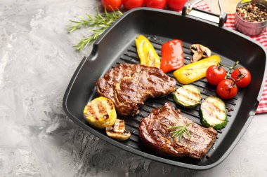 Izgara biftek, mantar, sebze ve baharatlı tava. Gri desenli masa, yakın plan. Metin için boşluk