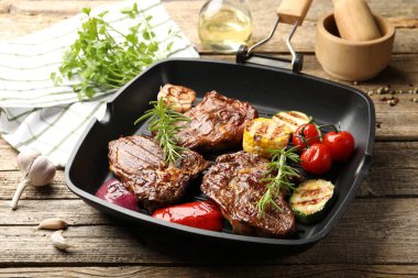 Tavada ızgara biftek, biberiye ve sebzeler ahşap masada, yakın plan.