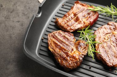 Izgara biftekli tava ve gri desenli masada biberiye, yakın plan.