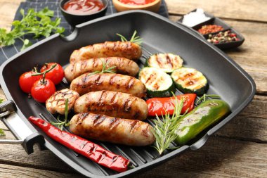 Tavada ızgara sosis, sebze, baharat ve soslar ahşap masada, yakın plan.