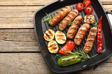 Tavada ızgara sosis, sebze ve baharat, ahşap masa, üst manzara. Metin için boşluk