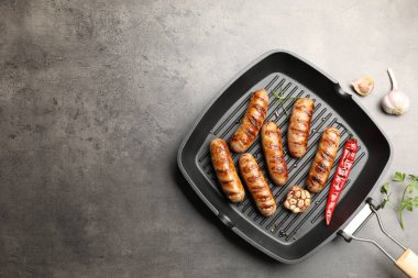 Izgara sosis ve baharatlı tava. Gri desenli masa, üst manzara. Metin için boşluk