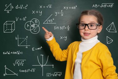 Yeşil karatahtaya formüller ve çizimlerle bakan çocuk