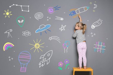 Gri arkaplanda tebeşirle çizen küçük çocuk