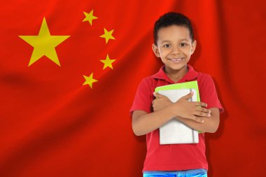 Çin bayrağına karşı defterleri olan küçük bir çocuk. Dil okulu