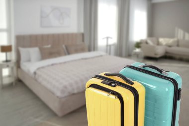 Spacious hotel room with comfortable furniture and guest suitcases, selective focus