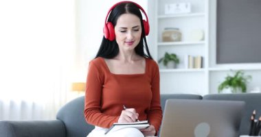 Evde dizüstü bilgisayarla sınavdan geçerken not alan kadın