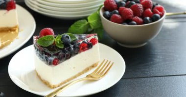 Böğürtlenli nefis peynirli kek ve siyah ahşap masada nane şekeri, yakın plan. Kamera sola hareket ediyor