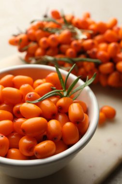 Taze deniz dikenli böğürtlen kasede ve bej masada yapraklar, yakın çekim
