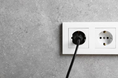 Gri duvardaki prizdeki güç prizi, yakın plan. Metin için boşluk