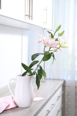 İçerideki ahşap dolaptaki sürahide güzel zambak çiçekleri.