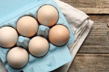 Yumurta kartonunda çiğ tavuk yumurtası, ahşap masa, üst manzara. Metin için boşluk