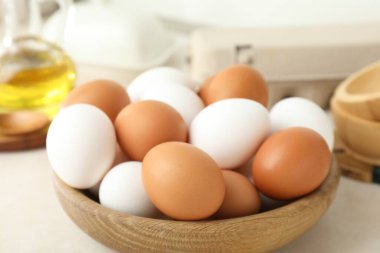 Raw chicken eggs and oil on white counter, closeup