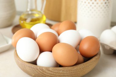 Raw chicken eggs and oil on white counter, closeup