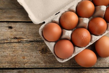 Yumurta kartonunda çiğ tavuk yumurtası, ahşap masa, üst manzara. Metin için boşluk