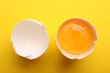 Sarı arka planda kırılmış tavuk yumurtası, üst manzara.