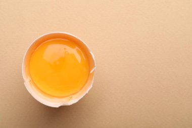 Bej arka planda kırılmış bir tavuk yumurtası, üst manzara. Metin için boşluk