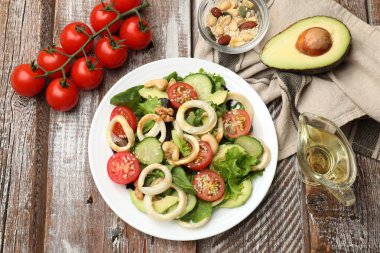 Ahşap masa üzerinde mürekkep balığı halkaları ve malzemeleriyle nefis bir salata.