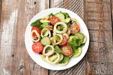 Ahtapot yüzüklü lezzetli salata, avokado, fındık ve sebzeler ahşap masada, üst manzara