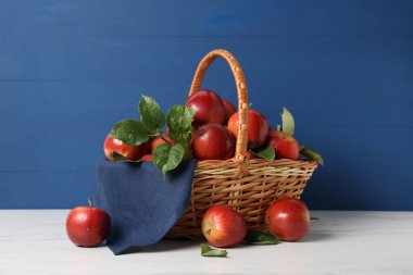 Taze olgun elmalar sepetin içinde beyaz masada.