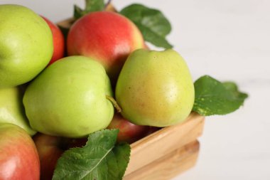 Beyaz masadaki sandıkta taze olgun elmalar, yakın plan.