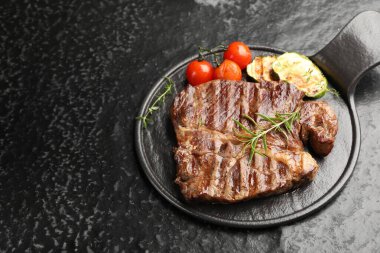 Biberiyeli ızgara biftek, kabak ve domatesli koyu dokuma masa. Metin için boşluk