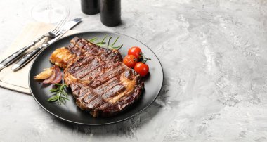 Biberiyeli, soğanlı, domatesli ve çatal bıçaklı lezzetli ızgara biftek, yakın plan. Metin için boşluk