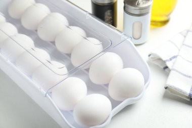 Beyaz masadaki kabın içinde çiğ tavuk yumurtası, yakın plan.