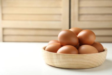 Beyaz masadaki kasede çiğ tavuk yumurtası, yakın plan. Metin için boşluk